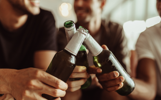 Three men clinking open beer bottles together