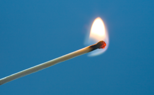 Burning match on blue background