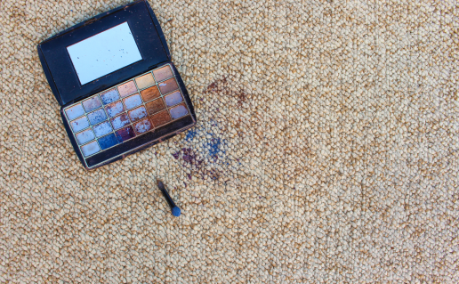 Eyeshadow palette and colorful makeup stains on carpet