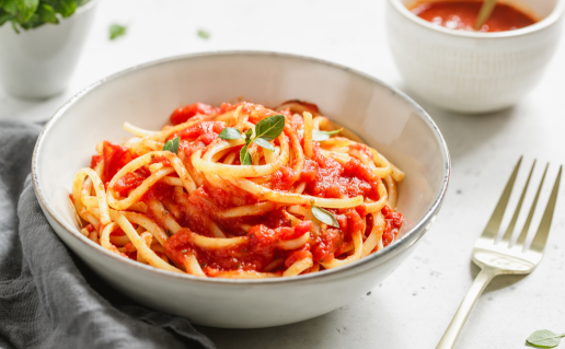 White bowl of spaghetti with tomato sauce