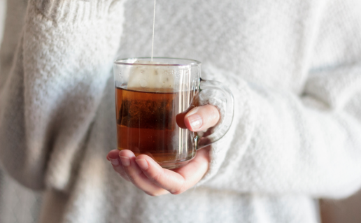 Woman in sweater holding glass tea mug