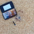 Eyeshadow palette and colorful makeup stains on carpet