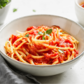 White bowl of spaghetti with tomato sauce