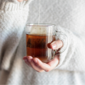 Woman in sweater holding glass tea mug